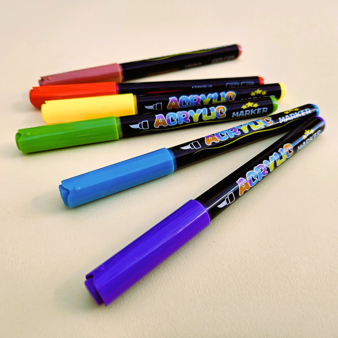 Set of acrylic markers with colorful caps on a beige background