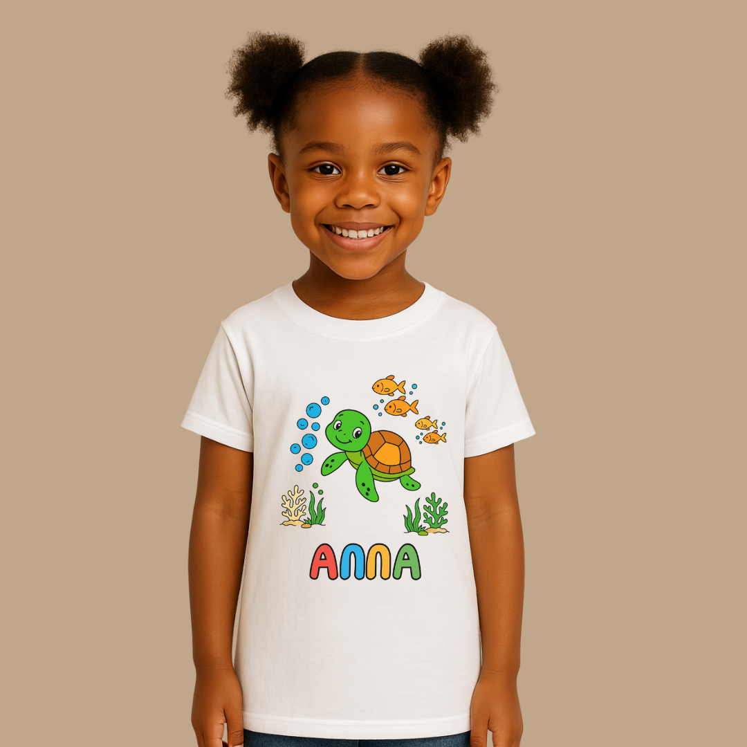 Child wearing a white t-shirt with a turtle and fish design and the name 'Anna'.