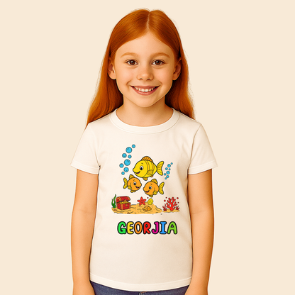 Young girl wearing a white t-shirt with cartoon fish and 'GEORGIA' text on a beige background