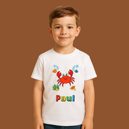 Child wearing a white t-shirt with a colorful crab design and the name 'Paul' on a brown background