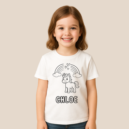 Child wearing a white t-shirt with a unicorn and rainbow design, standing against a beige background.