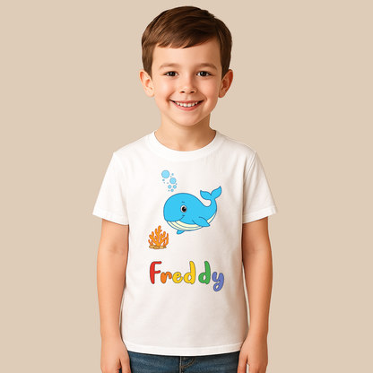 Child wearing a white t-shirt with a blue whale graphic and the name 'Freddy' on a beige background
