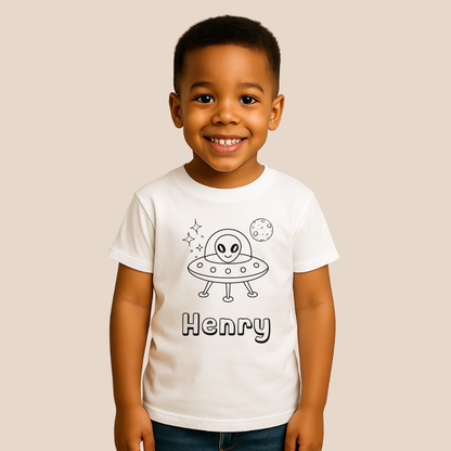 Child wearing a white t-shirt with an alien and UFO design, and the name 'Henry' on a beige background.