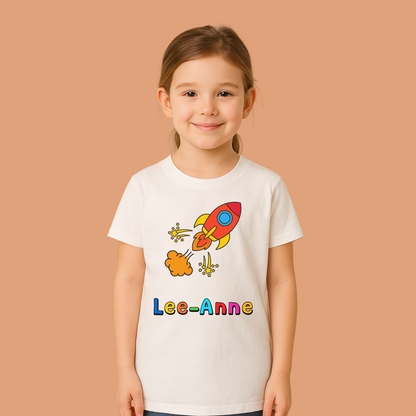 Child wearing a white t-shirt with a colorful rocket design and 'Lee-Anne' text on a beige background