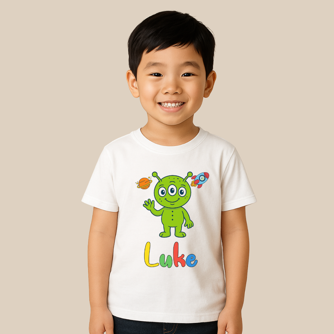 Child wearing a white t-shirt with a green alien design and the name 'Luke' on a beige background